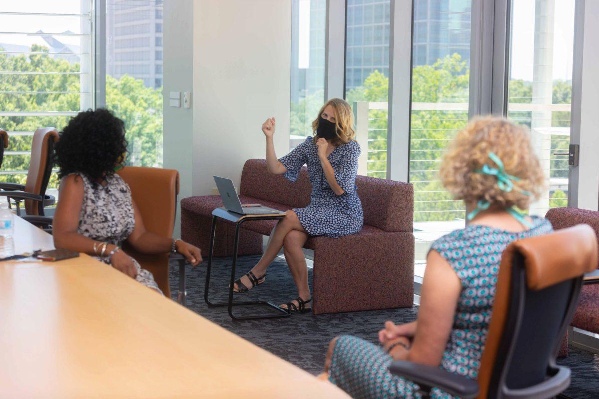 Three staff members talking in the library conference room, photo