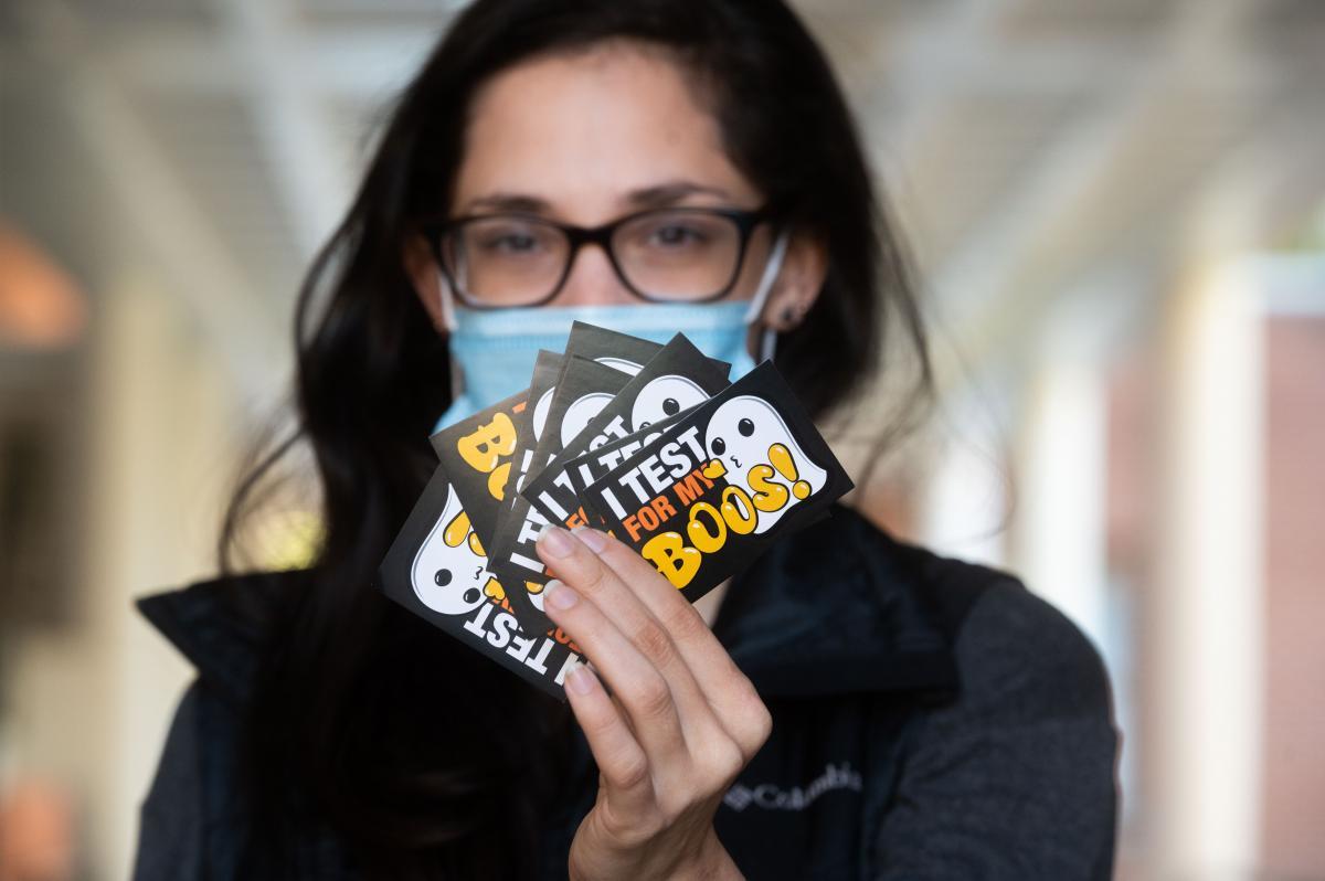 A staff member holding up a "I test for my boos" sticker.