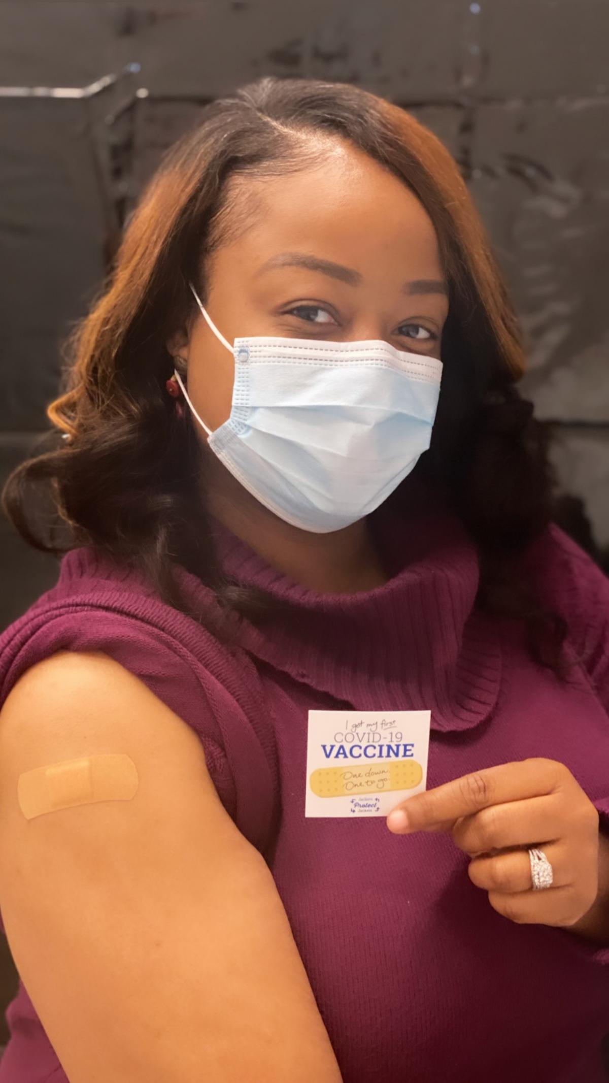 Quinae holding a vaccination sticker, photo